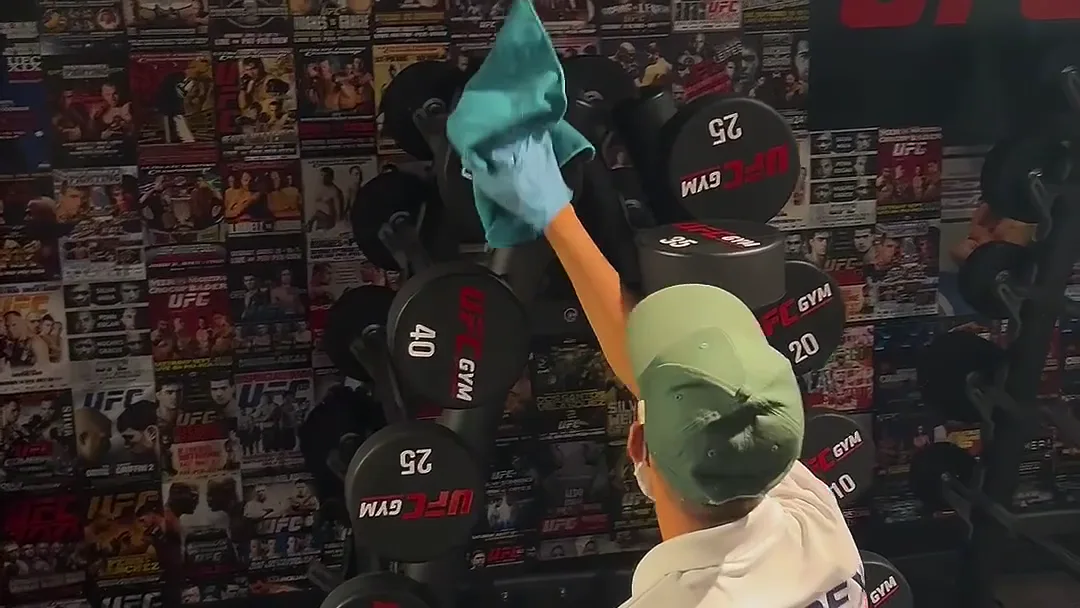 Apex cleaner sanitising dumbbells at a Sydney UFC Gym